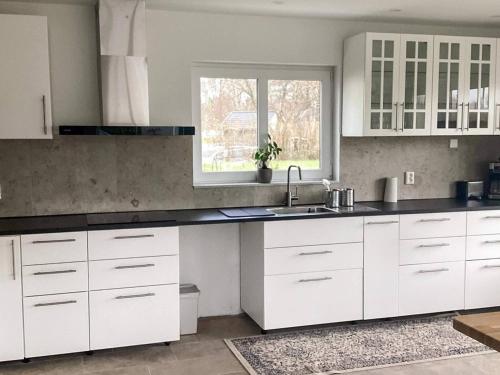 5 star holiday home in FALKENBERG في Anderstorp: مطبخ بخزائن بيضاء ومغسلة