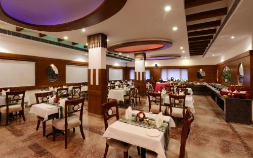 a restaurant with white tables and chairs and a buffet at Keshav Clarks Inn Gadag in Gadag