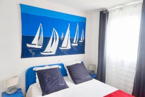 a bedroom with a bed with a painting of sailboats at Chez Ti Julio - Appartment Premium in Sainte-Anne