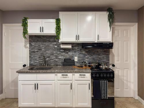a kitchen with white cabinets and a black stove at 20 Off The Jungle House 10 min Beach & FLL Airport in Fort Lauderdale