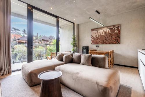 ein Wohnzimmer mit Couch und großem Fenster in der Unterkunft MODERN AND COMFORTABLE JUNGLE VISTA HOTEL Ubud Bali By JV with a relaxing atmosphere in Ubud