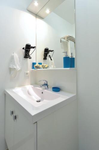 une salle de bain blanche avec un lavabo et un miroir dans l'établissement Djanea Luxury Apartment - Disneyland Paris, à Serris