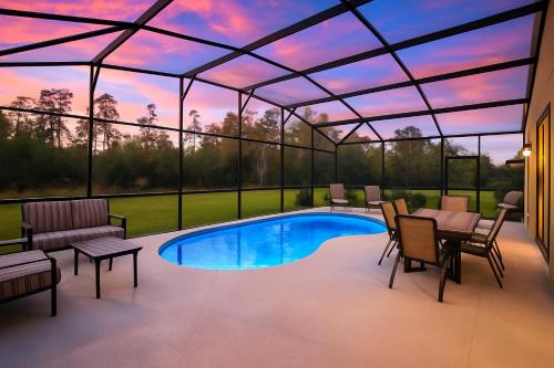 a patio with a pool and a table and chairs at Exclusive 8BR Family Villa - Pool, BBQ, Game Room & Themed Bedrooms! in Kissimmee