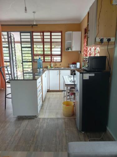 a kitchen with white cabinets and a black refrigerator at Kio Farm Retreat 2 in Kiserian
