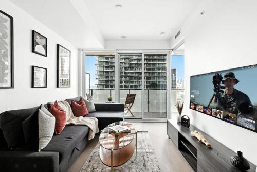 a living room with a couch and a flat screen tv at Chic Downtown Retreat with Private Patio in Toronto