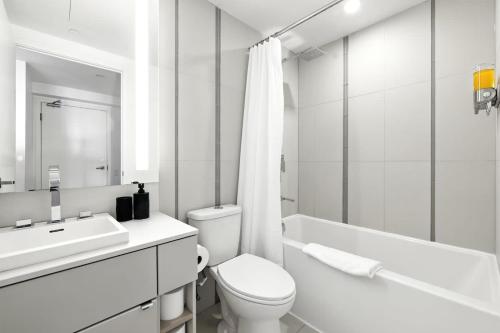 a white bathroom with a toilet and a sink at Chic Downtown Retreat with Private Patio in Toronto