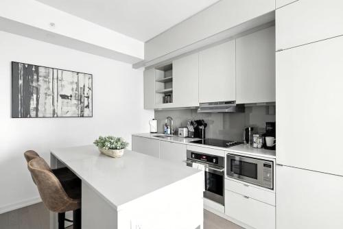 a white kitchen with white cabinets and a counter at Chic Downtown Retreat with Private Patio in Toronto