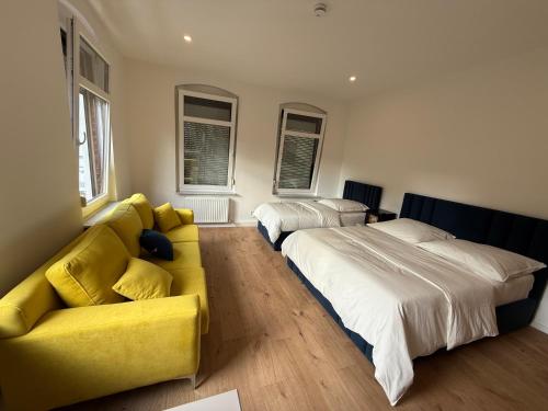 ein Schlafzimmer mit 2 Betten und einem gelben Sofa in der Unterkunft Hotel &Restaurant Meteora in Glauchau