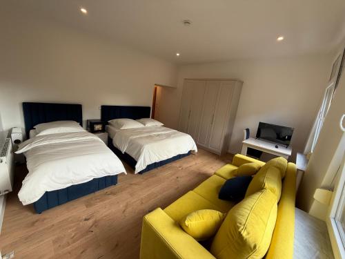 ein Wohnzimmer mit 2 Betten und einem gelben Sofa in der Unterkunft Hotel &Restaurant Meteora in Glauchau