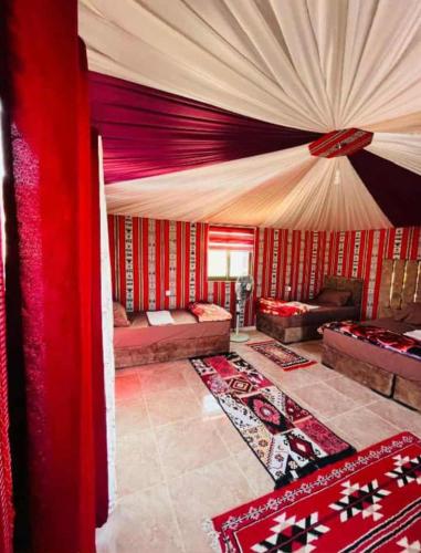 un soggiorno con tende e tappeti rossi e bianchi di Red Mountain Camp a Wadi Rum