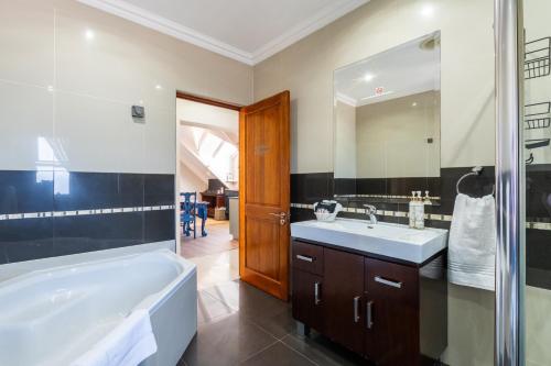a bathroom with a tub and a sink and a shower at Amara Mountain View George in George