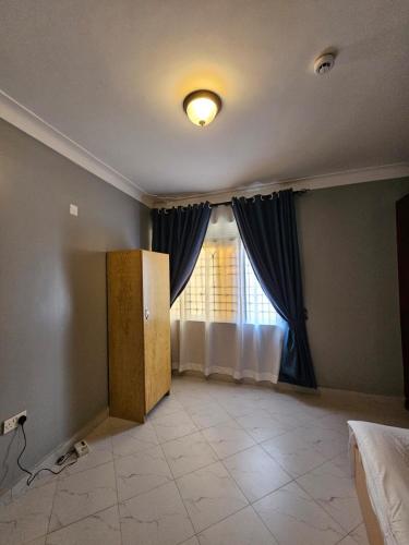 an empty room with a window with curtains and a floor at SBJ's Home in Entebbe