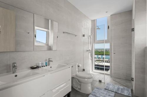 een witte badkamer met toilet en douche bij Ocean Vista Aruba in Palm-Eagle Beach