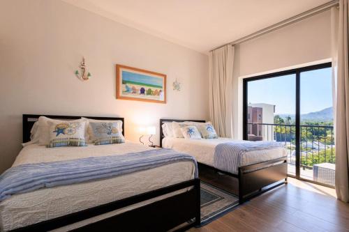 a bedroom with two beds and a balcony at Cozy 2BD Condo, Near Beach in San Felipe de Puerto Plata