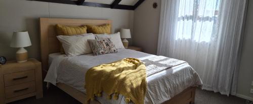 a bedroom with a bed with white sheets and a window at A Touch of Tuscany at Hillsborough in New Plymouth