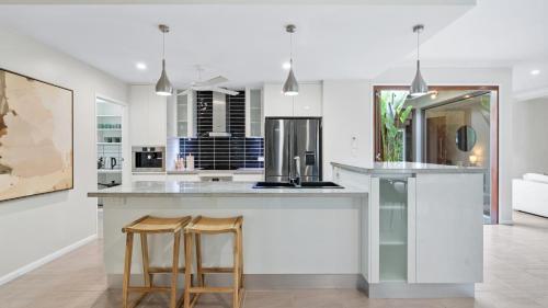 een keuken met een groot eiland met twee barkrukken bij Shambala at Palm Cove in Palm Beach