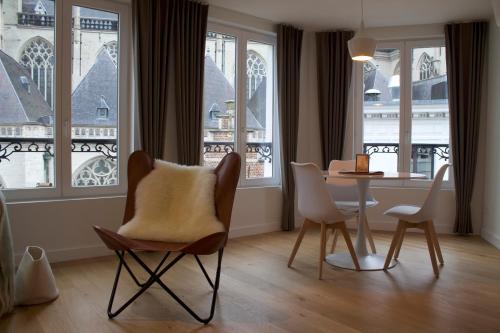 Una sala de estar con mesa y sillas y ventanas. en Cozy Central Apartment with Cathedral View on the 3rd floor, en Amberes