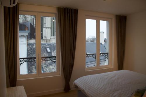 1 dormitorio con 2 ventanas, 1 cama y balcón en Cozy Central Apartment with Cathedral View on the 3rd floor, en Amberes