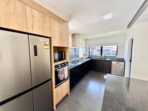 a kitchen with a stainless steel refrigerator and a sink at New 4BR Family Home in Greenhill Park, Chartwell in Hamilton