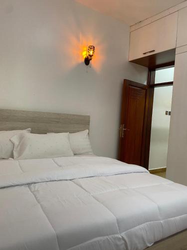 a bedroom with a large white bed with a light on the wall at Opal Heights Hotel Nansana in Kyebando