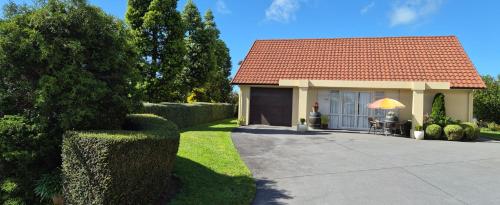 a small house with a red roof and a driveway at A Touch of Tuscany at Hillsborough in New Plymouth