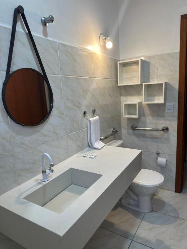 a bathroom with a sink and a toilet and a mirror at CANAS Praia Hotel Lounge in Florianópolis