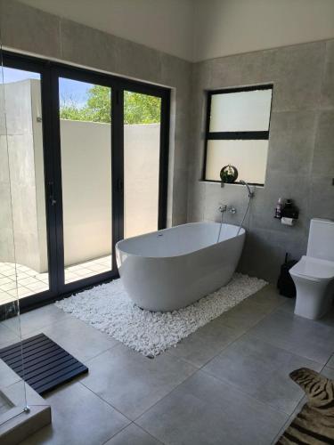 a large bathroom with a tub and a toilet at Eagle's Retreat in Marloth Park