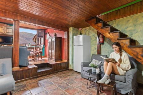 a woman sitting in a chair reading a book in a tiny house at Montegrande, entorno mágico rodeado de montañas in La Plaza