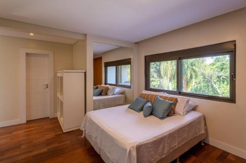 een slaapkamer met twee bedden en een groot raam bij Refúgio de Luxo à beira do Lago Passaúna, in Ferraria