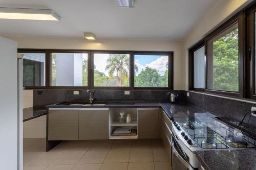 een keuken met een wastafel en een aantal ramen bij Refúgio de Luxo à beira do Lago Passaúna, in Ferraria