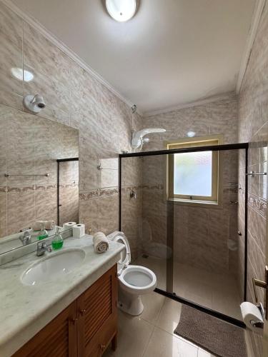 a bathroom with a shower and a toilet and a sink at Villa das Araras Residence in Porto Seguro