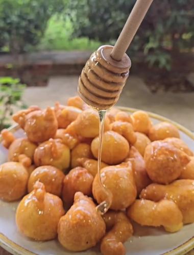 a plate of food with a honey dipped spoon at Guesthouse Lord Byron in Tepelenë
