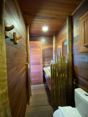 a wooden bathroom with a toilet and a sink at Villa Caravelas Praia de Moitas in Amontada