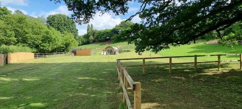 a wooden fence in a field with a gate at The Mainstay Pod at Hidden Wood Glamping in Corsley