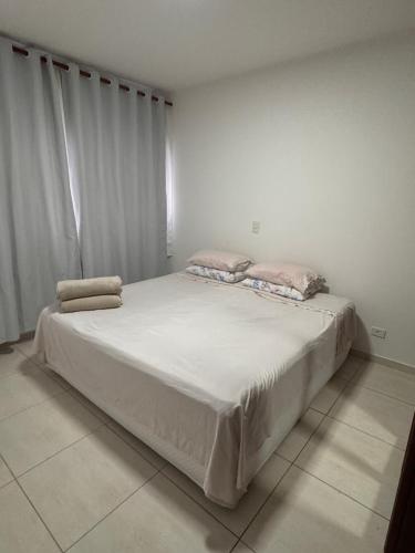 Un dormitorio con una gran cama blanca con dos almohadas. en Apartamento completo com Serviço de Quarto em Alphaville, en Barueri