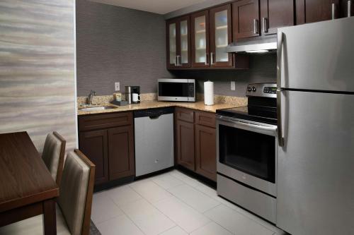 a kitchen with wooden cabinets and stainless steel appliances at Residence Inn by Marriott New Orleans Metairie in Metairie