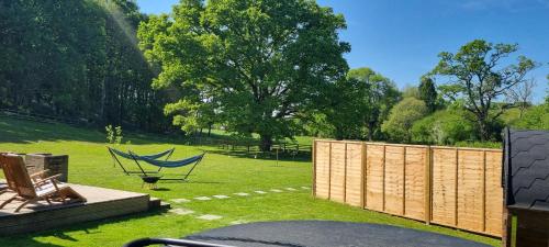 a yard with a hammock and a fence at The Mainstay Pod at Hidden Wood Glamping in Corsley
