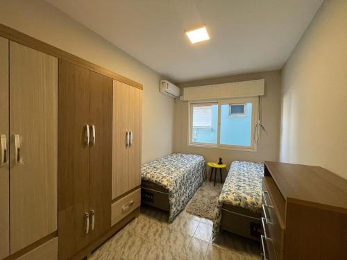 a small room with two beds and a cabinet at Apartamento na praia in Capão da Canoa