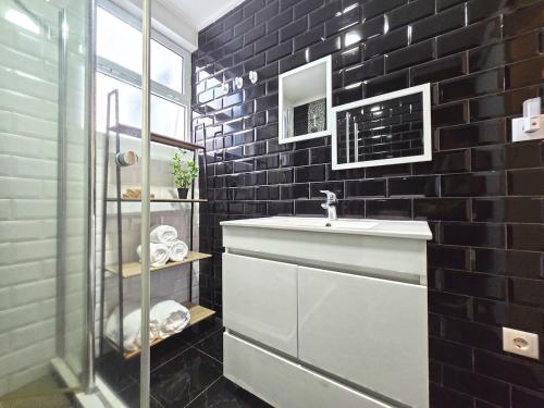 een badkamer met een wastafel en een zwarte bakstenen muur bij Casa da Maré Azul in São Roque