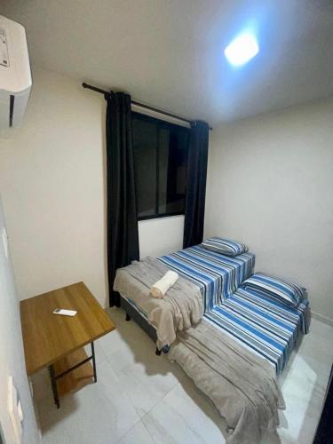 um quarto com 2 camas e uma mesa de madeira em Excelente apartamento a passos da praia em Cabedelo