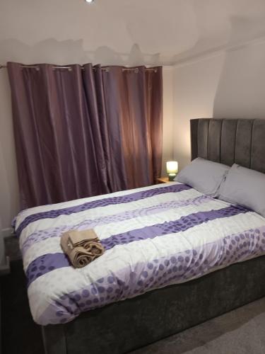 1 dormitorio con 1 cama con edredón morado y blanco en High class accommodation, en Bury