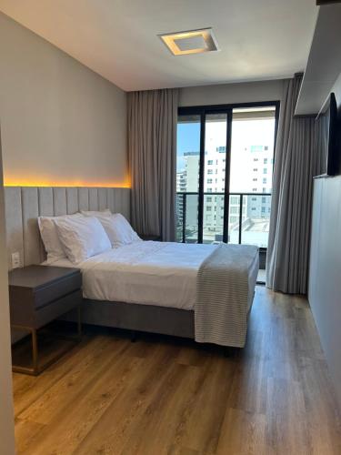 ein Schlafzimmer mit einem Bett und einem großen Fenster in der Unterkunft Apartamento 100m da Praia Brava - Itajaí in Itajaí
