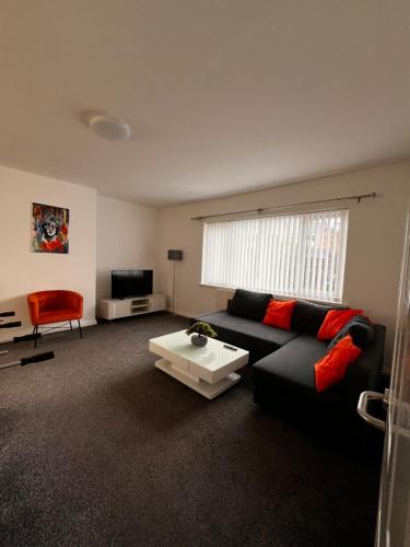 a living room with a black couch and a red chair at Just Stay in Warrington