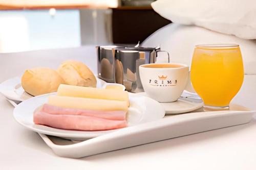 een dienblad met kaasbrood en een glas sinaasappelsap bij Prime Motel Piracicaba in Piracicaba