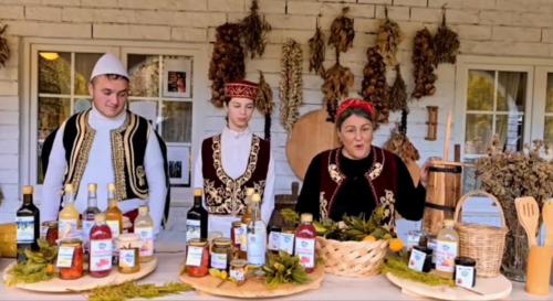 a group of three people in costumes standing behind a table with bottles of wine at Guesthouse Lord Byron in Tepelenë