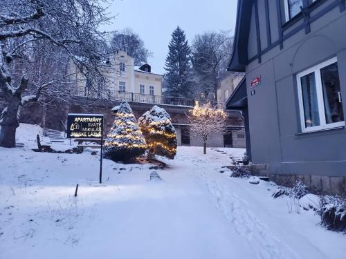 a snow covered yard with christmas trees and a sign at Apartmány Svatý Mikuláš in Janske Lazne