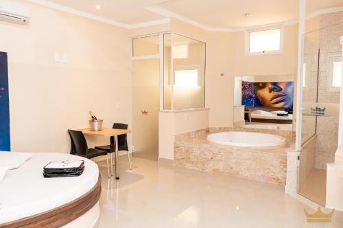 a white bathroom with a tub and a table at Prime Motel Piracicaba in Piracicaba