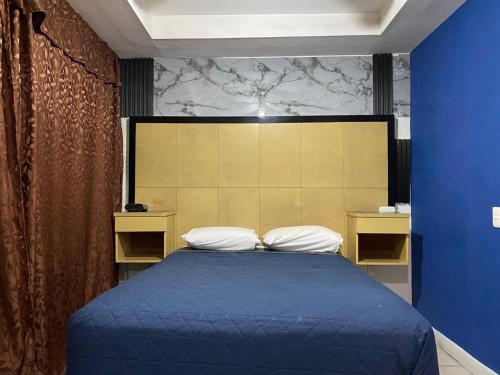 a bedroom with a blue bed with two pillows at Hotel Puerto México Aeropuerto in Mexico City