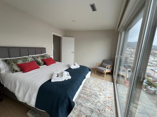 una camera da letto con un grande letto con cuscini rossi e una finestra di Alborada Duplex a Moaña