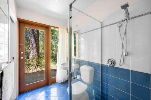 a bathroom with a toilet and a glass shower at Sweeds - Belle Escapes Jervis Bay in Vincentia